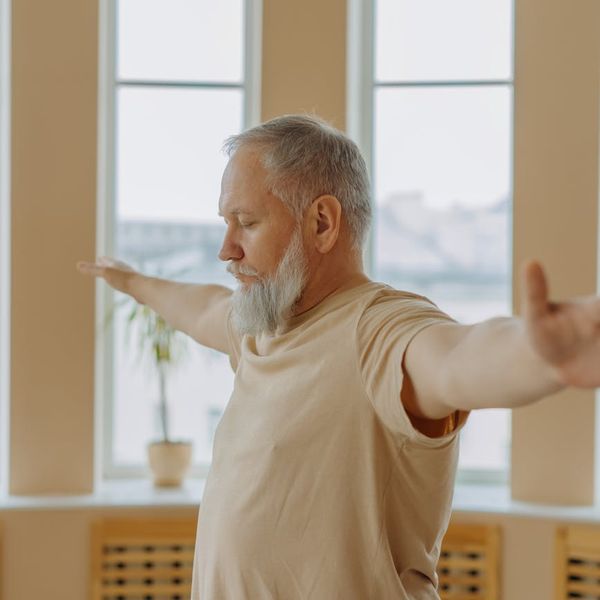 Person stretching gently indoors, with soft light from a window.